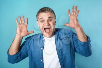 Screaming mature man on color background�