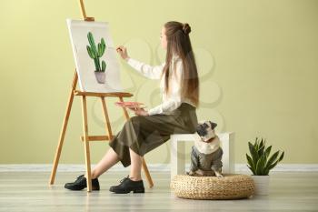 Teenage artist with cute pug dog at home�