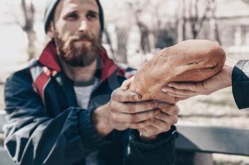 Passer-by giving bread to poor homeless man outdoors�