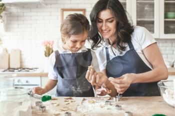 Happy mother with daughter preparing cookies in kitchen at home�