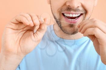 Man flossing teeth on color background, closeup�