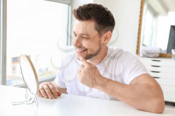 Man with healthy teeth looking in mirror at home�