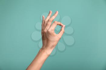 Female hand showing OK gesture on color background�