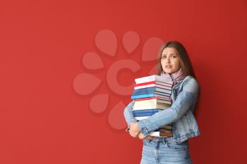 Stressed young woman with books on color background�