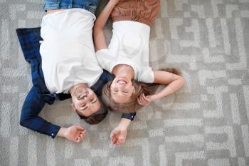 Young couple lying on soft carpet at home, top view�
