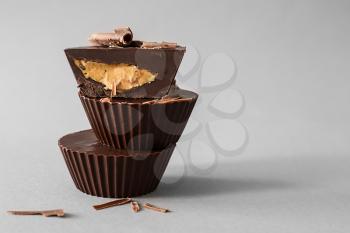 Tasty chocolate peanut butter cups on grey background�