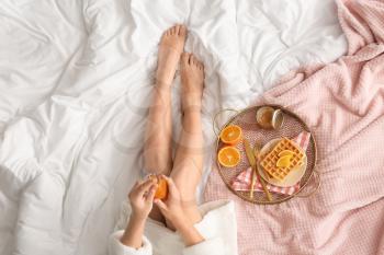 Woman having tasty breakfast in bed�