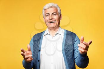 Portrait of happy senior man on color background�