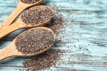 Spoons with chia seeds on wooden table, closeup�