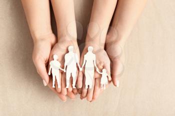 Hands of woman and child with figure of family on light background. Adoption concept�