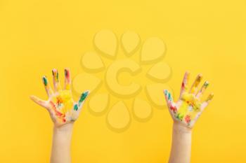 Child's hands in paint on color background�