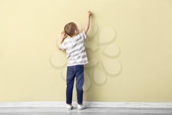 Little boy drawing on color wall�