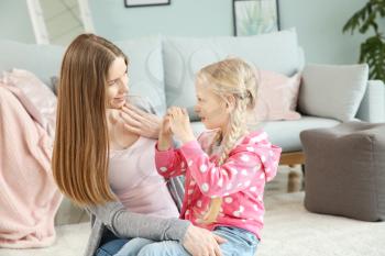 Mother teaching her deaf mute daughter to use sign language at home�