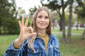 Young deaf mute woman using sign language outdoors�