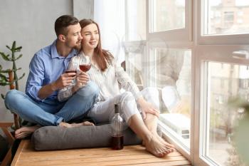 Happy couple drinking wine near window at home�
