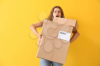 Shocked woman with cardboard boxes on color background�