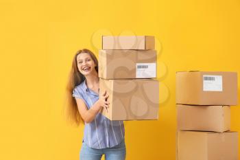 Young woman with cardboard boxes on color background�