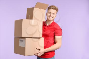 Young man with cardboard boxes on color background�