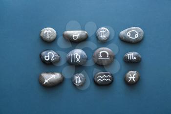 Stones with painted Zodiac signs on color background�