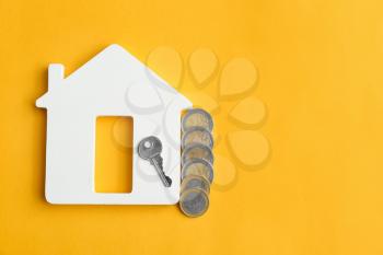 Figure of house, key and money on color background�