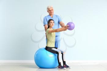 Mature physiotherapist working with young Asian woman in clinic�