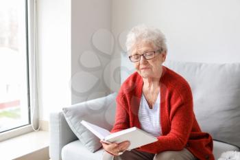 Senior woman reading book at home�