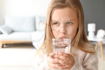 Cute little girl drinking water at home�
