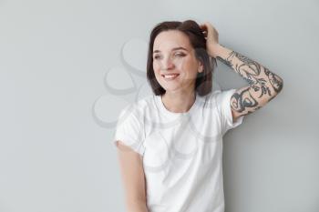 Stylish tattooed woman on light background�