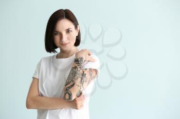 Beautiful tattooed woman on light background�