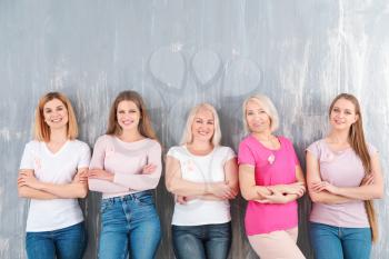 Beautiful women of different ages with pink ribbons on grey background. Breast cancer concept�