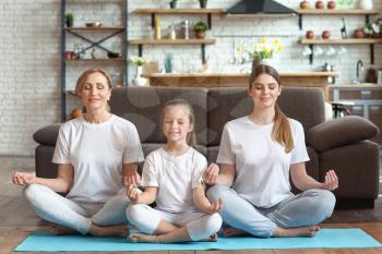 Little girl with her mother and grandmother meditating at home�