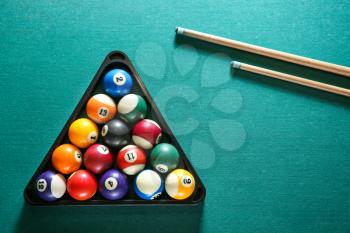 Billiard balls in triangle rack with cues on table�
