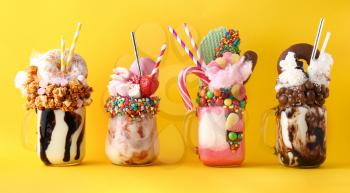 Different delicious freak shakes on color background�
