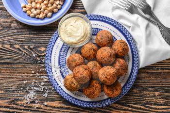 Plate with tasty falafel balls and sauce on wooden table�
