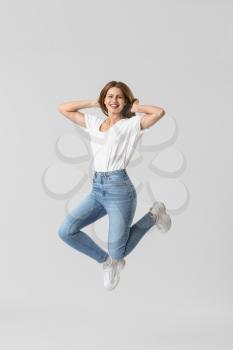 Jumping young woman in jeans on white background�
