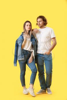 Stylish young couple in jeans on color background�