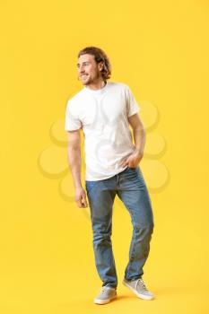 Stylish young man in jeans on color background�
