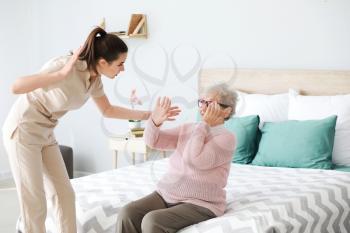 Caregiver mistreating senior woman in nursing home�