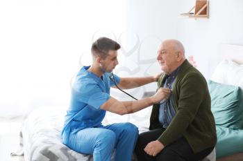 Medical worker examining senior man in nursing home�