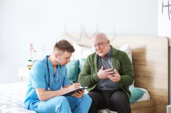 Medical worker with senior man in nursing home�