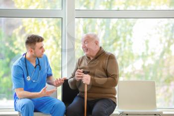Medical worker with senior man in nursing home�