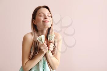 Happy young woman with money on color background�