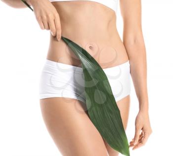 Beautiful young woman in underwear and with green leaf on white background�