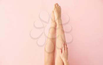 Beautiful young woman after laser hair removal procedure of legs on color background�