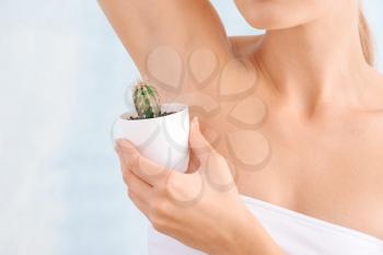 Beautiful young woman with cactus on light background. Depilation concept�