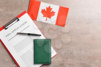 Visa application form, passport and Canadian flag on table. Concept of immigration�
