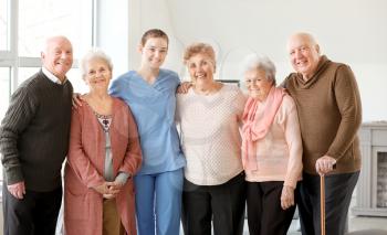 Young caregiver with group of senior people in nursing home�