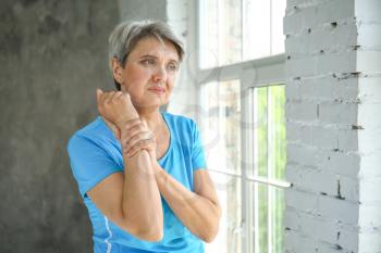 Mature woman suffering from pain in wrist at home�