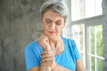 Mature woman suffering from pain in wrist at home�