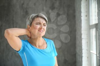 Mature woman suffering from neck pain at home�